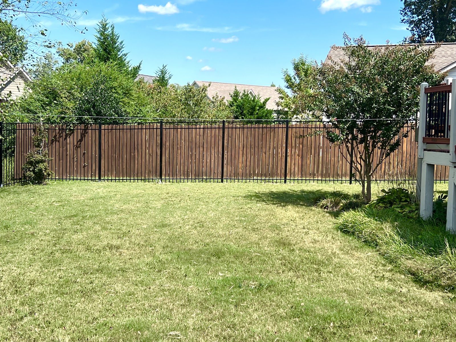 Stained wood privacy fence around a green backyard